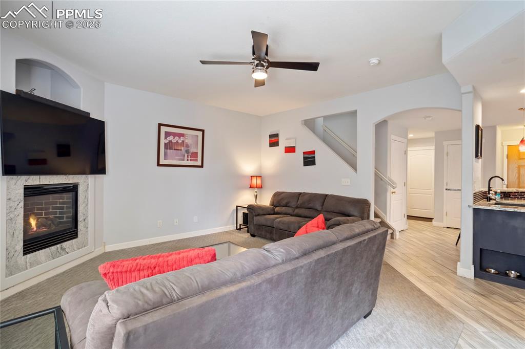 Image 6 of 42: Living area featuring ceiling fan, a fireplace, arched walkways, and light 