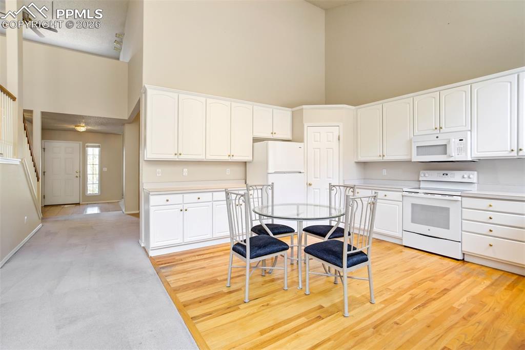 Image 14 of 44: Open-concept kitchen featuring white cabinetry, light-toned countertops, an