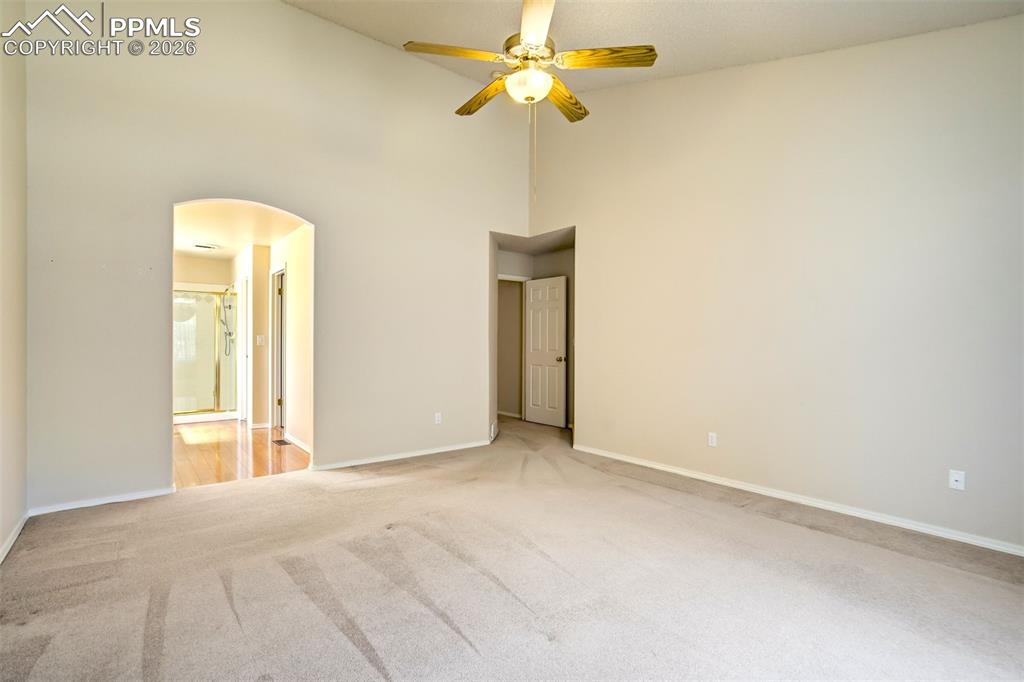 Image 18 of 44: Spacious room featuring vaulted ceilings, a ceiling fan with light fixture,
