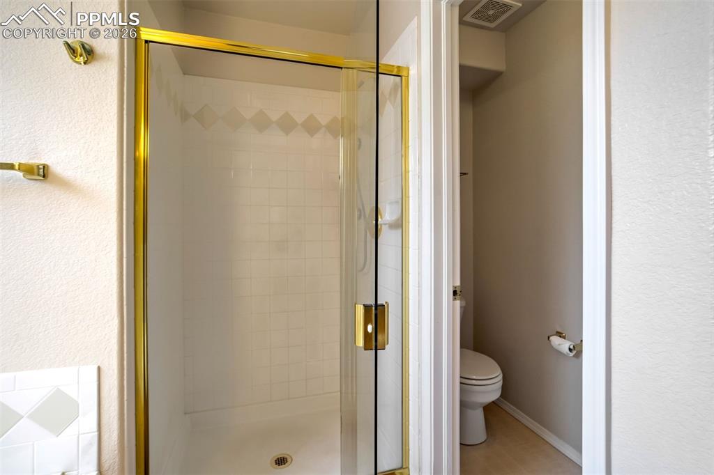 Image 20 of 44: Bathroom featuring a shower enclosure with a gold frame, clear glass door