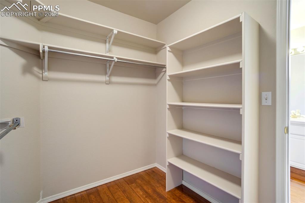 Image 21 of 44: Walk-in closet featuring wood-finish flooring, built-in shelving, and multi