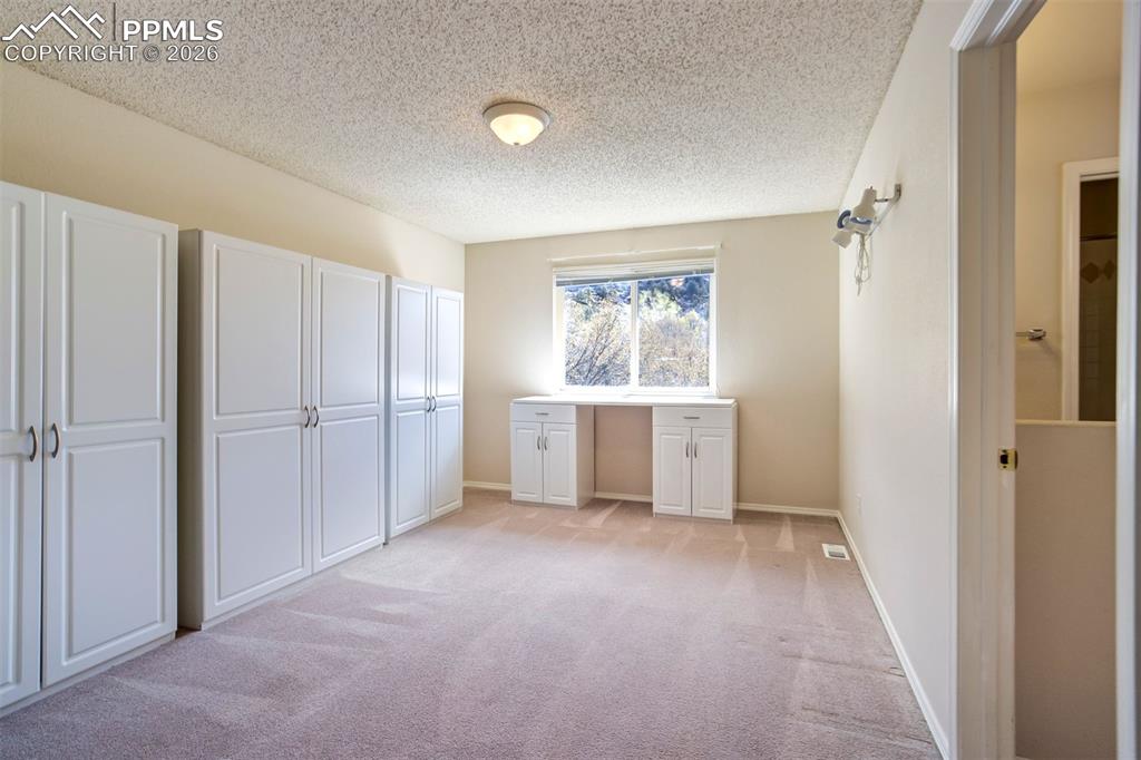Image 24 of 44: Room featuring extensive white wardrobes, a desk with lower cabinets and ca