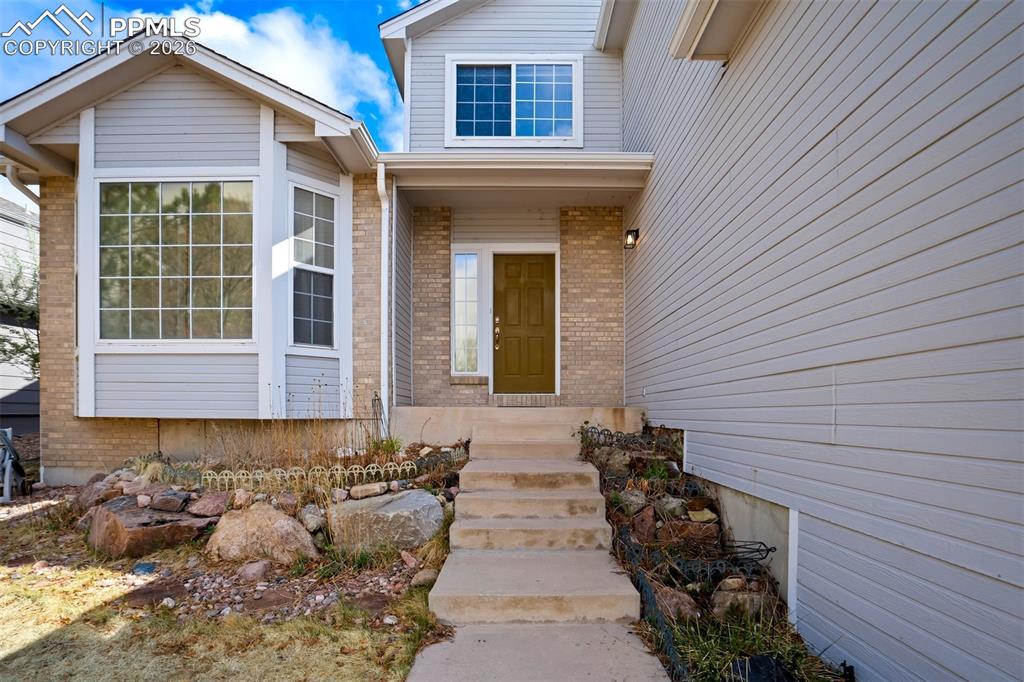 Image 3 of 44: Light gray siding and brick exterior featuring a bay window, concrete steps