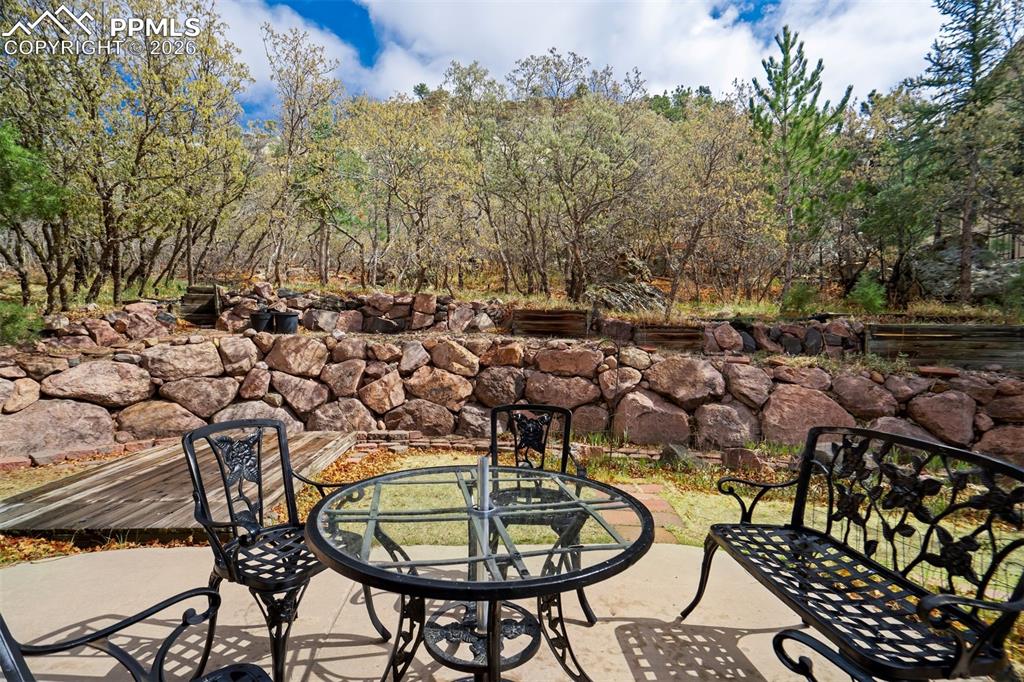 Image 33 of 44: Expansive patio area featuring a concrete surface and a natural stone retai