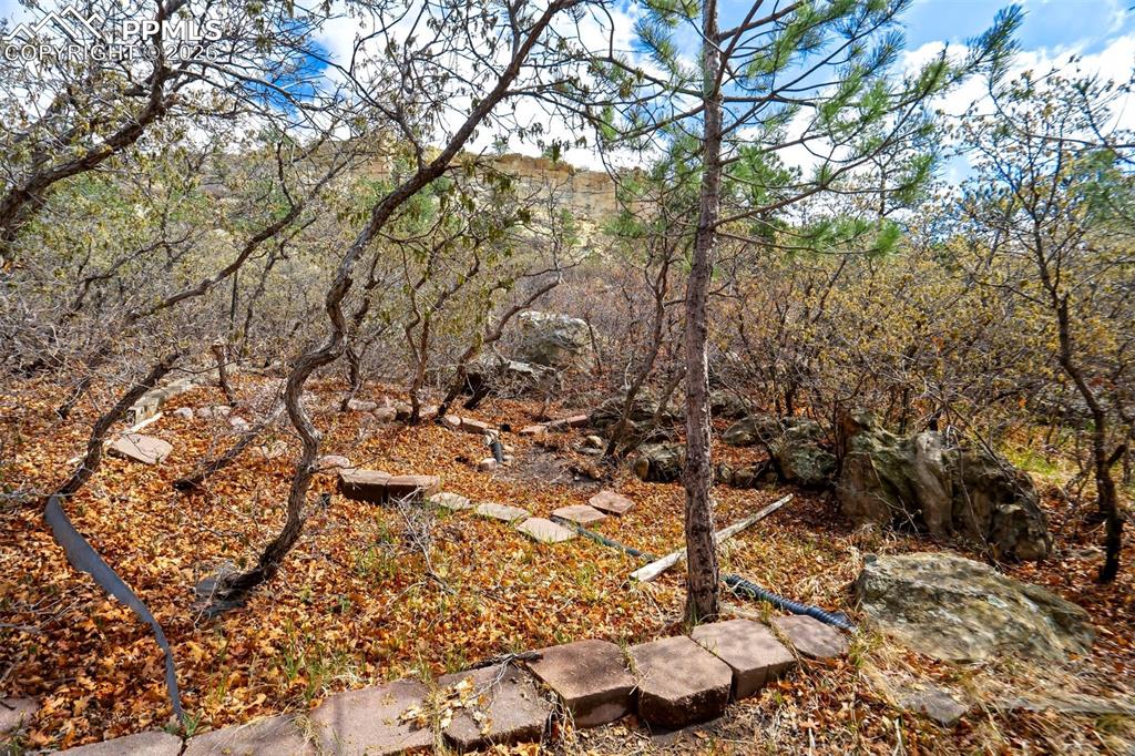 Image 36 of 44: Wooded landscape featuring natural rock formations and a flagstone path