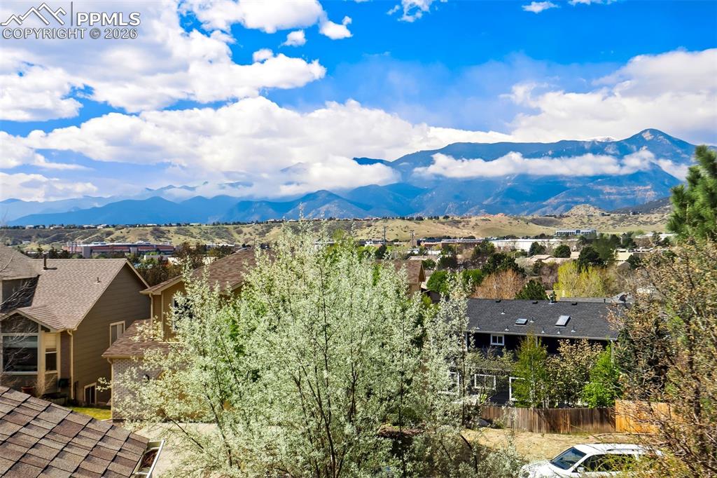 Image 41 of 44: Expansive mountain range backdrop with distant residential rooftops and lus