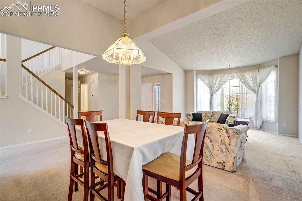 Image 6 of 44: Open-concept dining area with a chandelier, featuring a staircase with wood