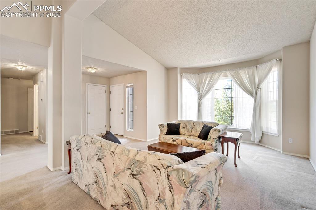 Image 9 of 44: Spacious living area featuring a large bay window, neutral wall tones, and 