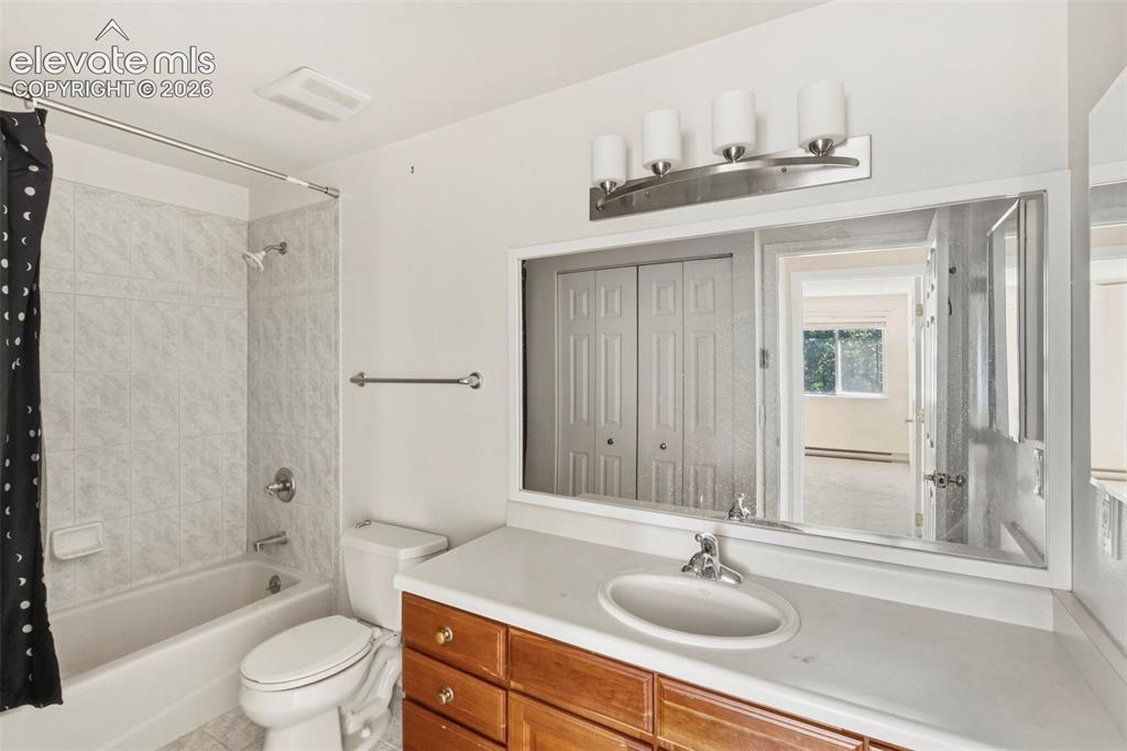Image 14 of 18: Bathroom featuring a built-in vanity with wood-finish cabinetry, a white co