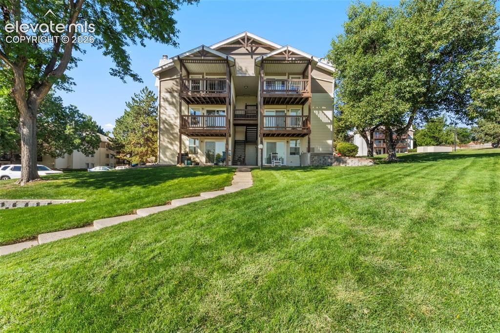 Image 3 of 18: Two-story balconies with dark wood railings, light-toned exterior siding, a