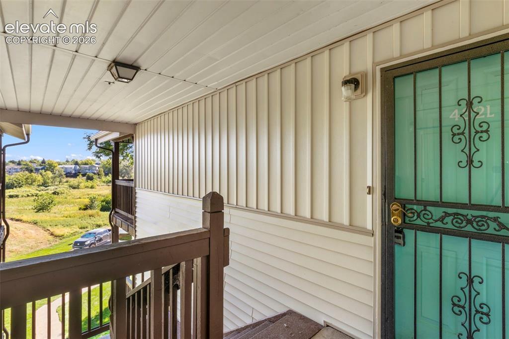Image 4 of 18: Covered entryway with white vertical siding and an ornamental security scre