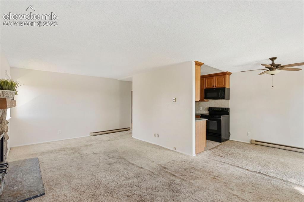 Image 7 of 18: Living area featuring a stone fireplace with hearth, a ceiling fan, and car