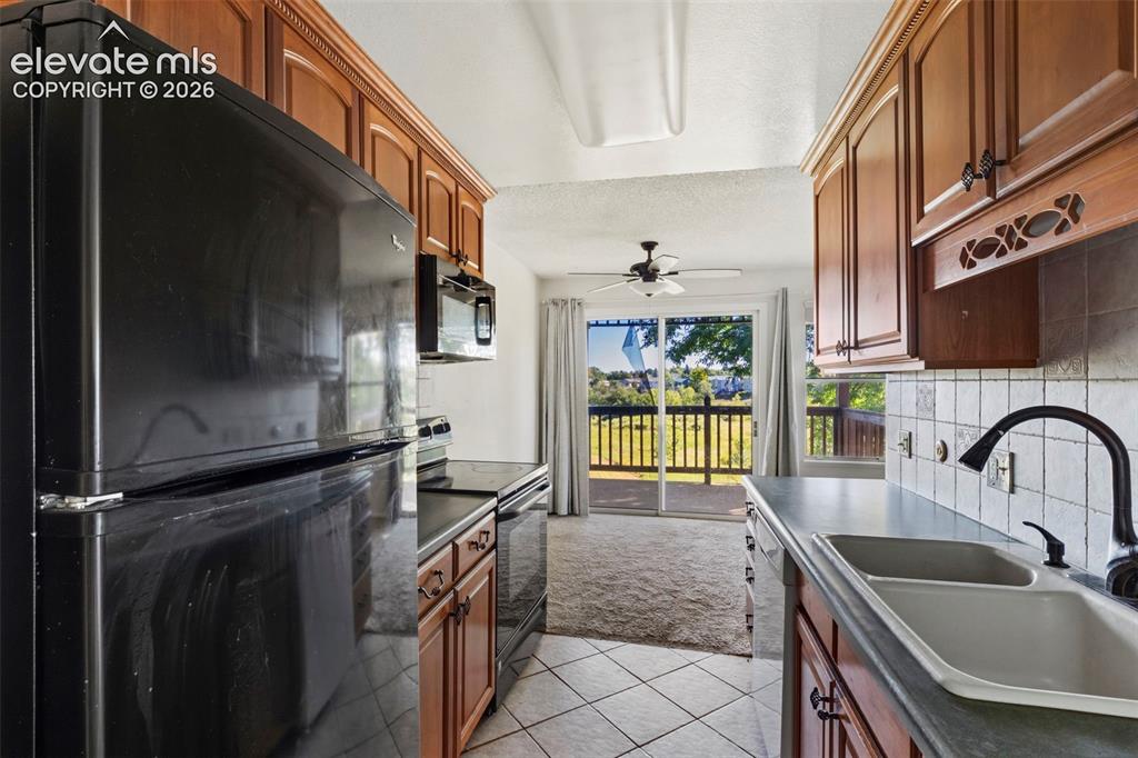 Image 9 of 18: Galley kitchen featuring wood cabinetry, tile flooring, and a double-basin