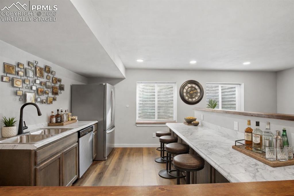 Image 28 of 40: Kitchen featuring dark wood-style floors, a breakfast bar, stainless steel 