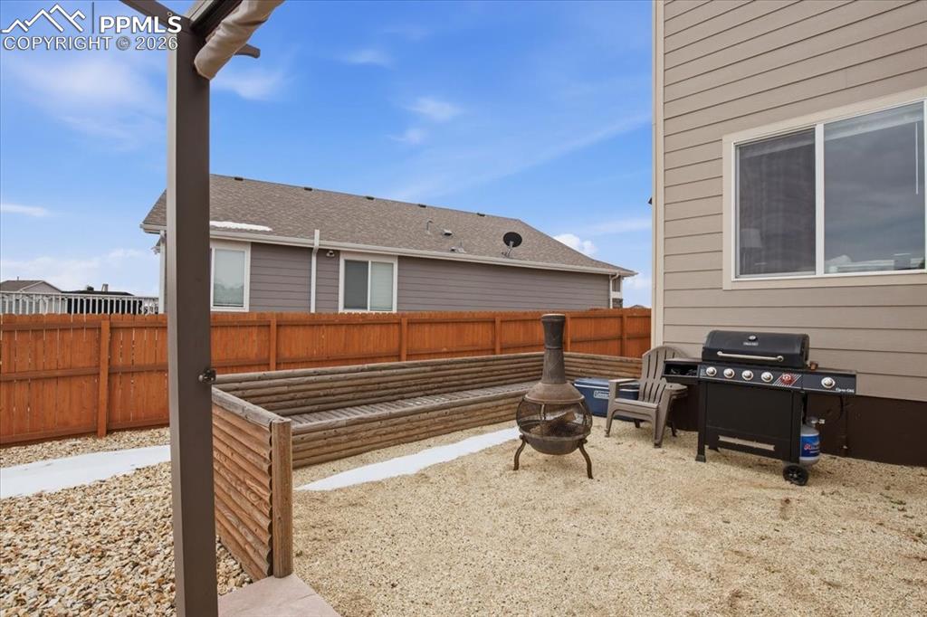 Image 37 of 40: Custom built log seating area with wood burning fire pit and outdoor grilli