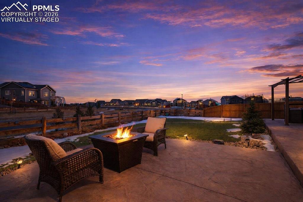 Image 6 of 40: Patio terrace at dusk featuring an outdoor fire pit, a patio, a residential