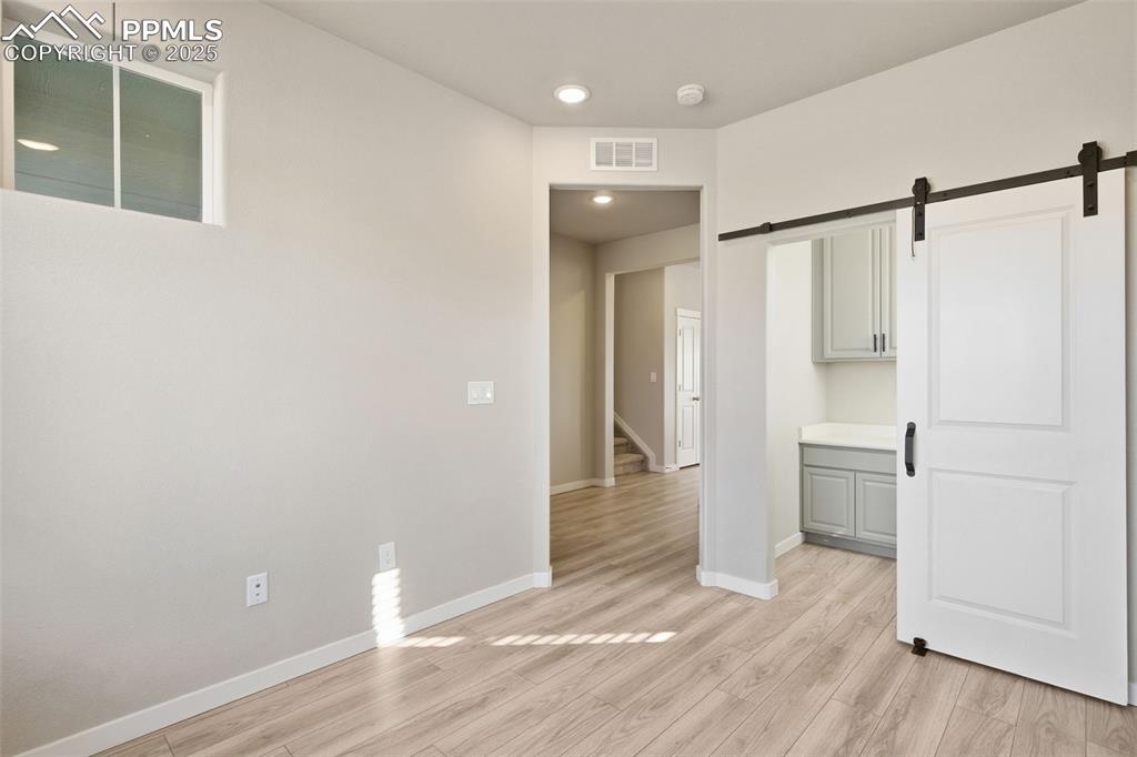 Image 9 of 50: Built in Small Office tucked away behind the barn door in this Bedroom/Offi