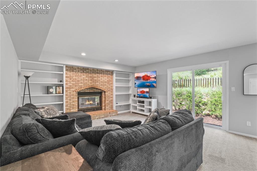 Image 11 of 50: Carpeted living room featuring built in features, a fireplace, and recessed