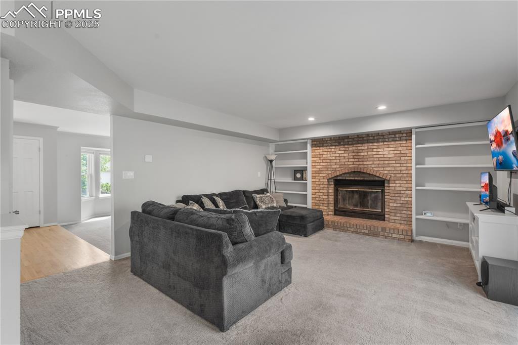 Image 12 of 50: Carpeted living area featuring a fireplace, recessed lighting, and built in