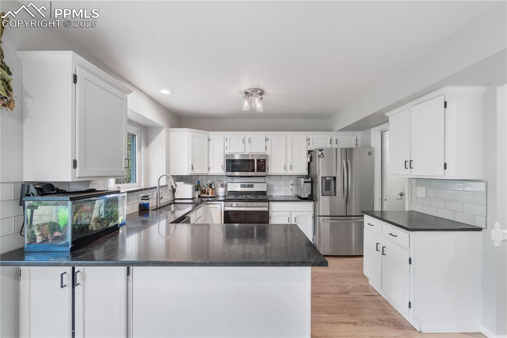 Image 17 of 50: Kitchen featuring stainless steel appliances, tasteful backsplash, a penins