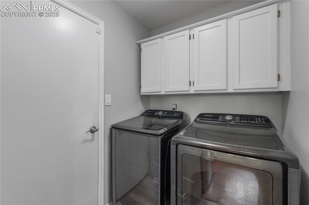 Image 20 of 50: Washroom with washing machine and clothes dryer and cabinet space
