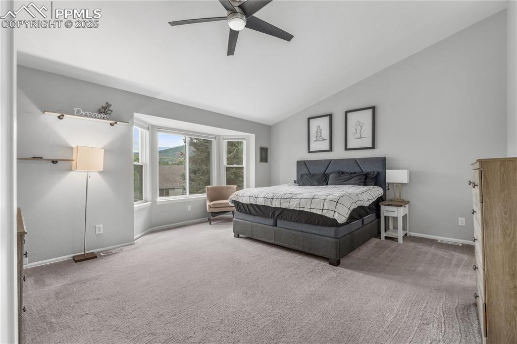 Image 22 of 50: Carpeted bedroom featuring vaulted ceiling and ceiling fan