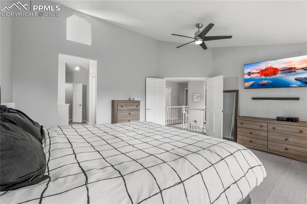 Image 24 of 50: Carpeted bedroom featuring high vaulted ceiling and ceiling fan
