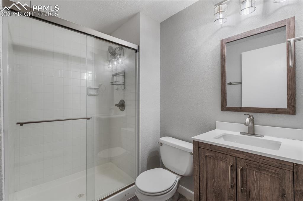 Image 38 of 50: Full bath featuring a textured wall, a stall shower, vanity, and a textured