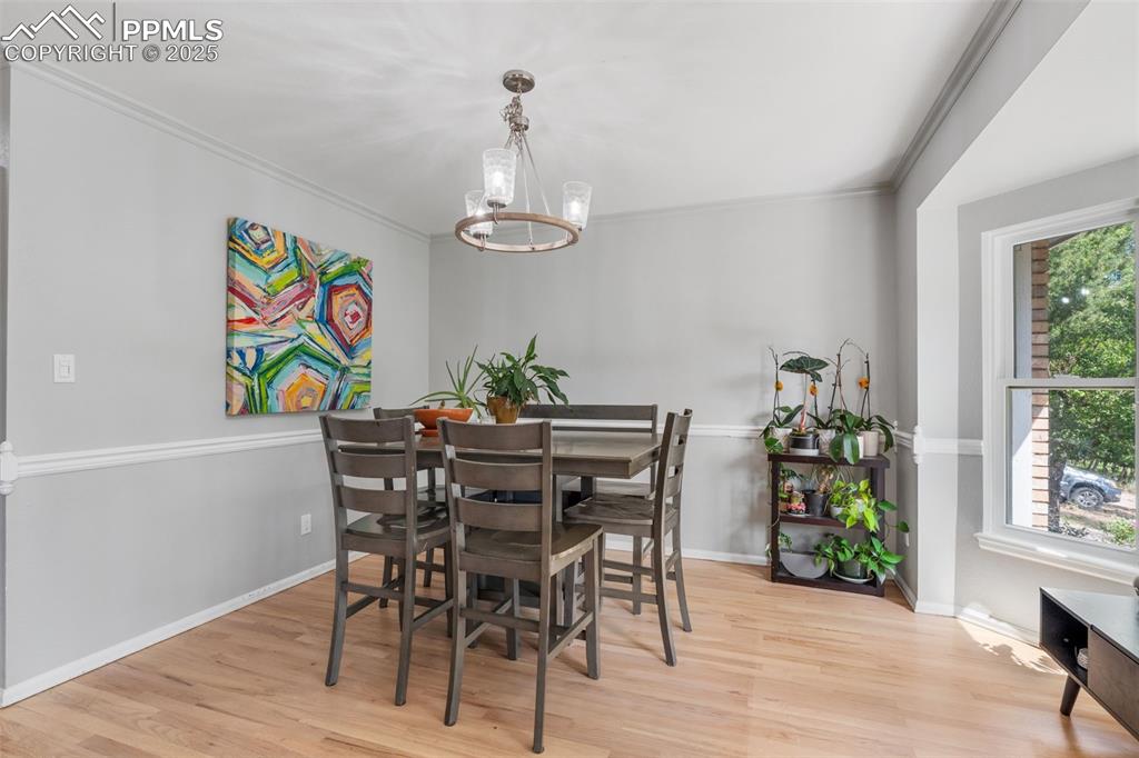 Image 7 of 50: Dining room featuring wood finished floors, a chandelier, and crown molding