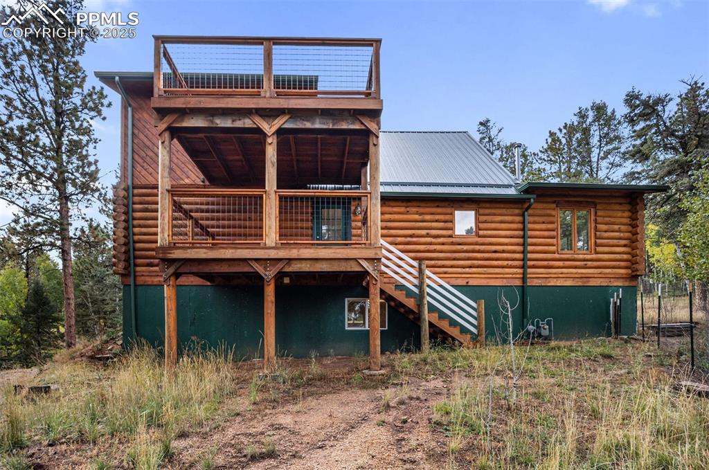 Image 31 of 48: Rear view of house featuring log exterior, stairs, a deck, and a metal roof