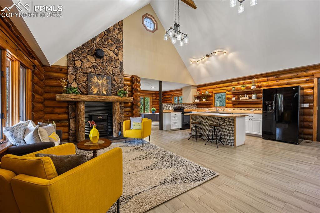 Image 5 of 48: Living area featuring log walls, high vaulted ceiling, and a pellet stove f