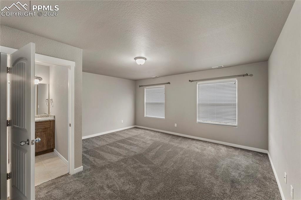 Image 10 of 21: Unfurnished bedroom featuring dark colored carpet, a textured ceiling, and