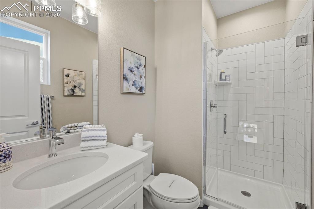 Image 14 of 37: The main floor bathroom has a beautiful tile and glass shower, quartz count