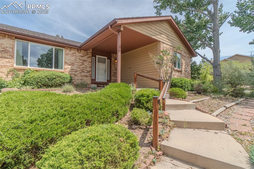 Image 4 of 48: Covered front porch with concrete steps leading to it.