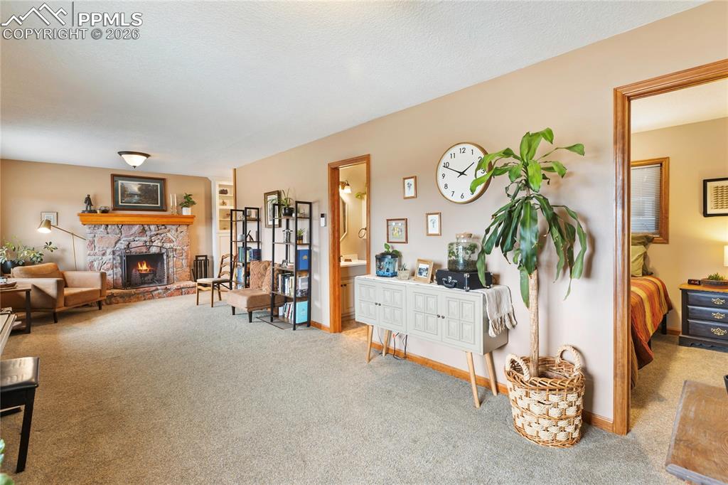 Image 14 of 42: The sitting room has a stone fireplace with a natural wood mantel and rich