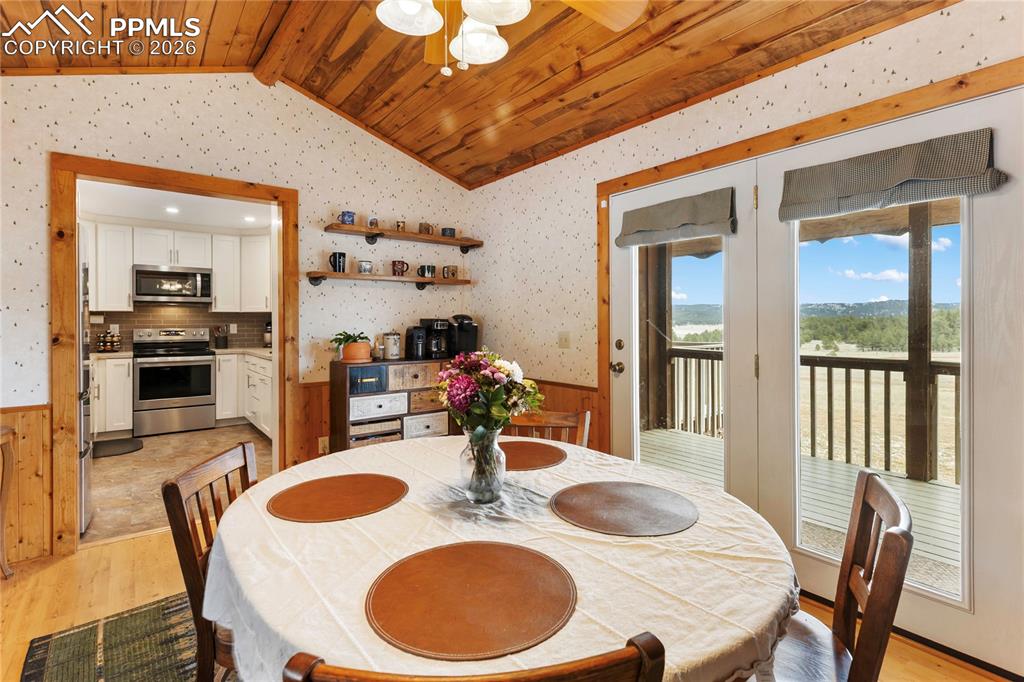 Image 5 of 42: The walkout dining space has a wainscoted wall and a vaulted ceiling, finis