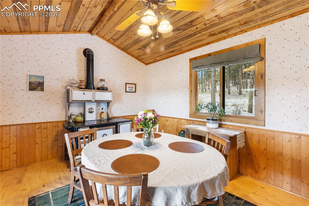 Image 7 of 42: The dining space has a wainscoted wall and a vaulted ceiling, finished with