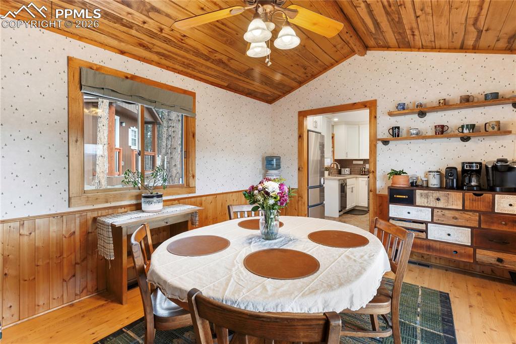 Image 8 of 42: The dining space has a wainscoted wall and a vaulted ceiling, finished with