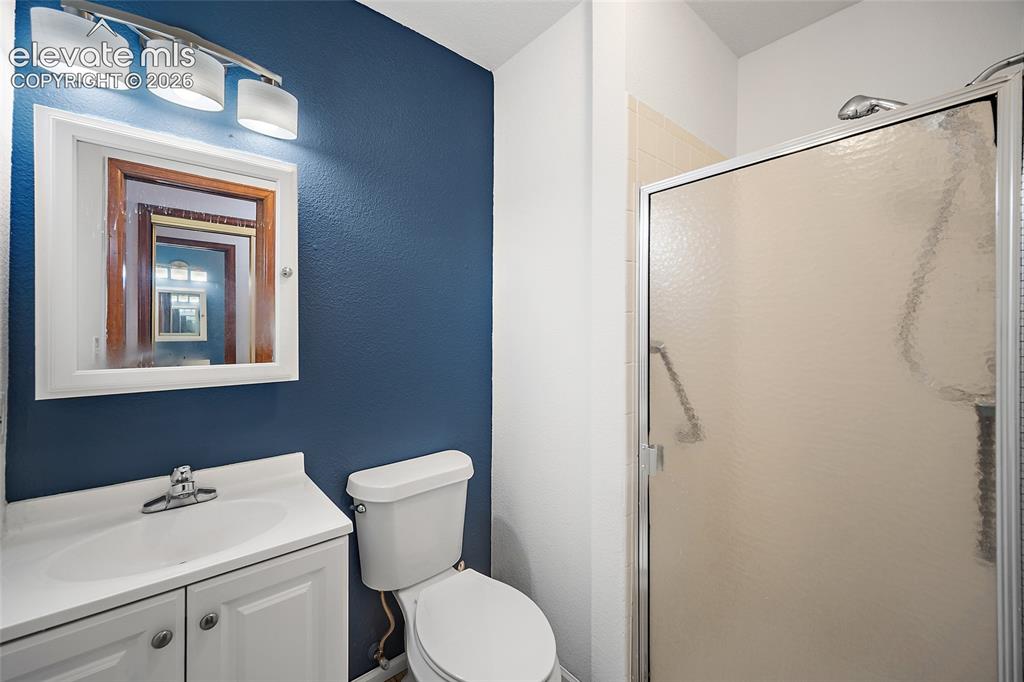 Image 11 of 26: Bathroom featuring a single vanity with storage, a white toilet, and a stan