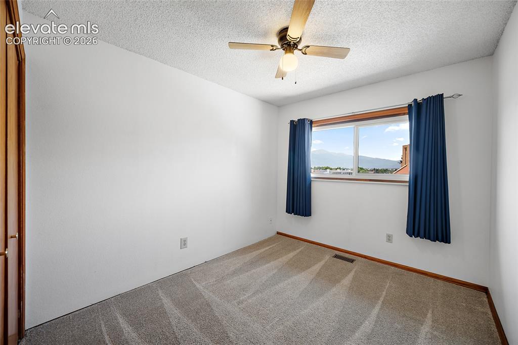 Image 12 of 26: Bright room featuring a window with mountain scenery, a ceiling fan, light-