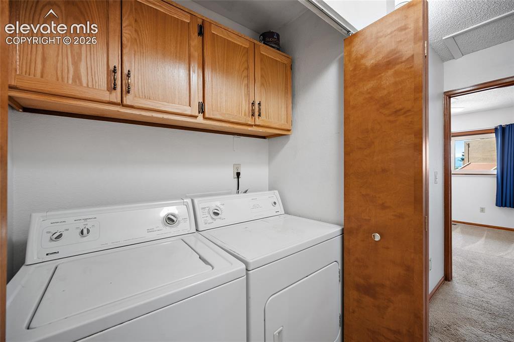 Image 16 of 26: Dedicated laundry area featuring white appliances and wood cabinetry with m