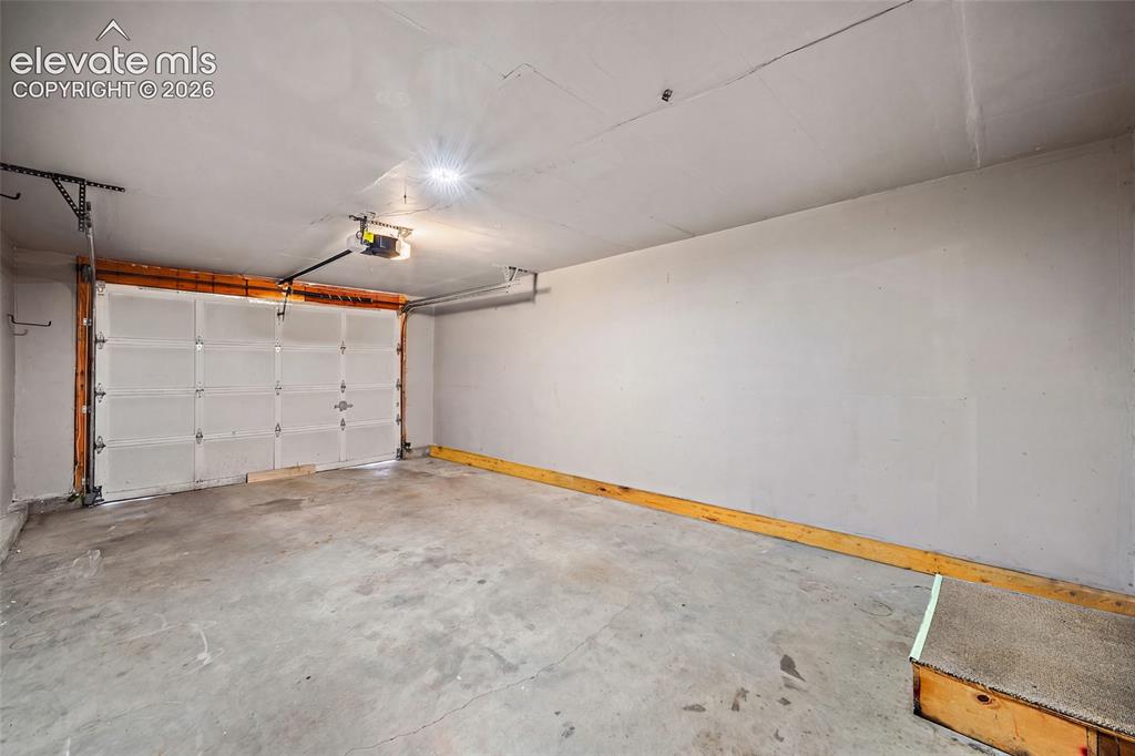 Image 20 of 26: Attached garage with concrete flooring, automatic garage door opener, and o