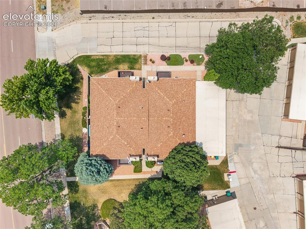 Image 24 of 26: Residential structure featuring a brown shingle roof, surrounded by mature