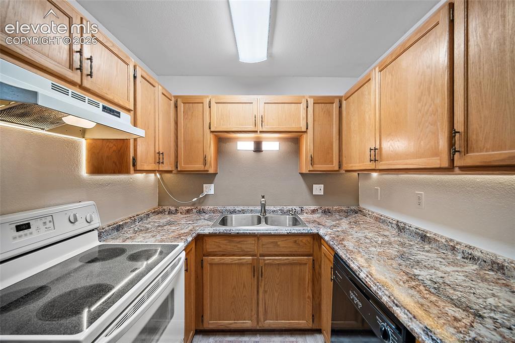 Image 5 of 26: U-shaped kitchen featuring wood-finish cabinetry, a double basin stainless