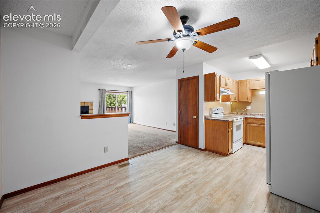 Image 6 of 26: Kitchen featuring wood-finish cabinetry, white appliances, and laminate cou