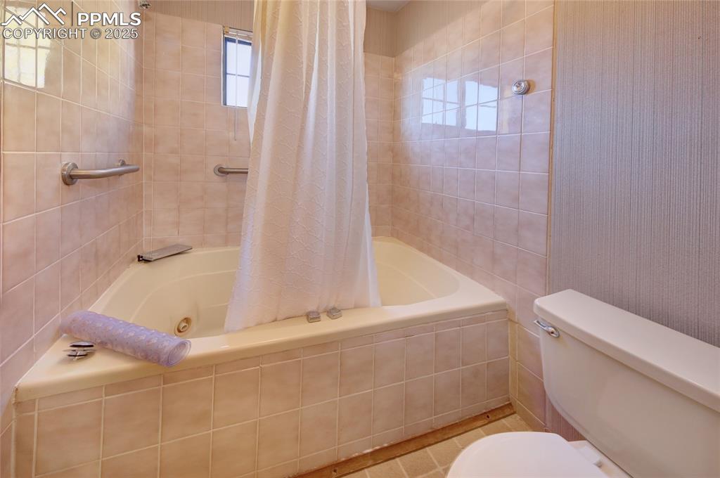 Image 23 of 33: Upper Full Bathroom with tiled shower / bath combo and toilet