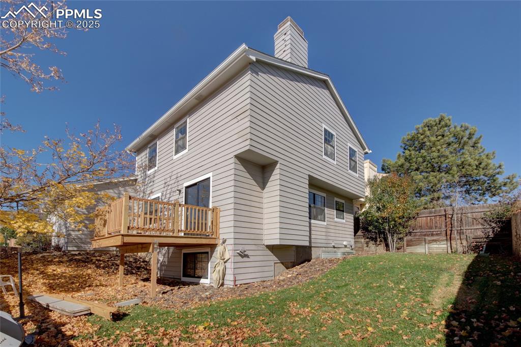 Image 30 of 33: Rear view of property featuring a wooden deck and a chimney