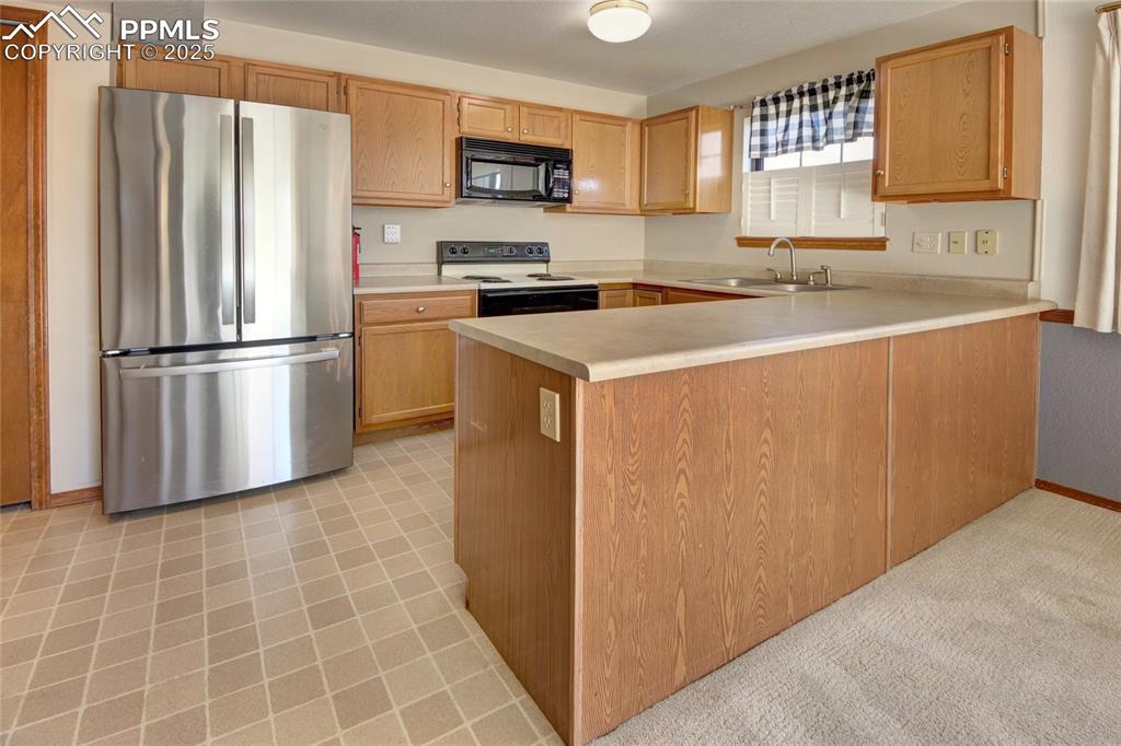 Image 7 of 33: Kitchen featuring freestanding refrigerator, light countertops, a peninsula