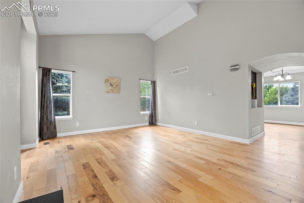 Image 11 of 50: Empty room with high vaulted ceiling, light wood-style flooring, plenty of