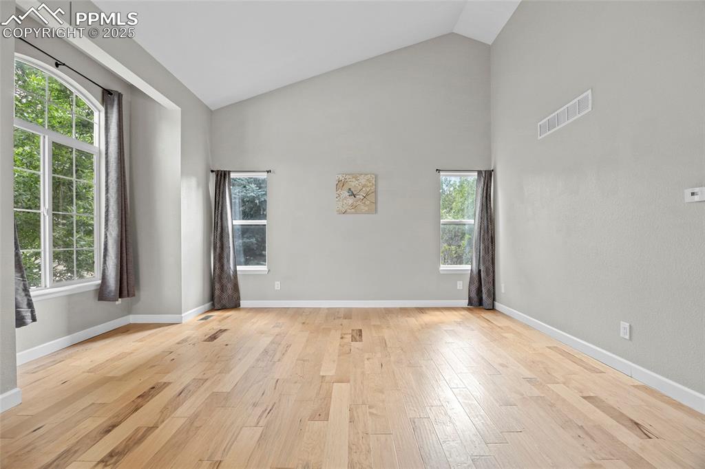 Image 13 of 50: Empty room featuring light wood-style floors and high vaulted ceiling